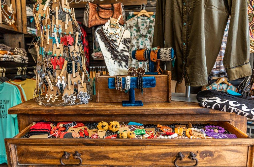 Western earrings and accessories in a wooden cabinet drawer with earrings hanging on a spinner