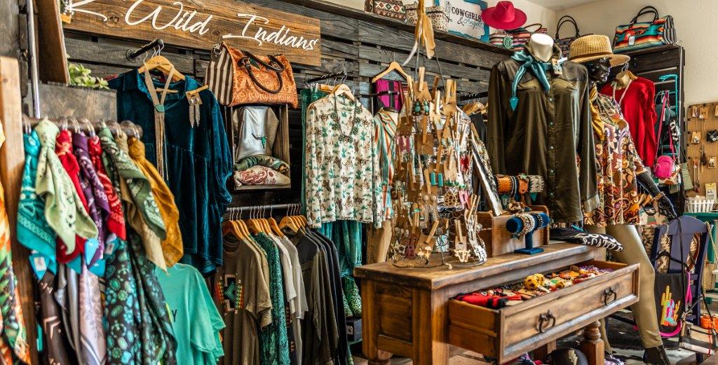 Women's Western Clothing hanging on a wooden wall with a wooden chest full of earrings and jewelry