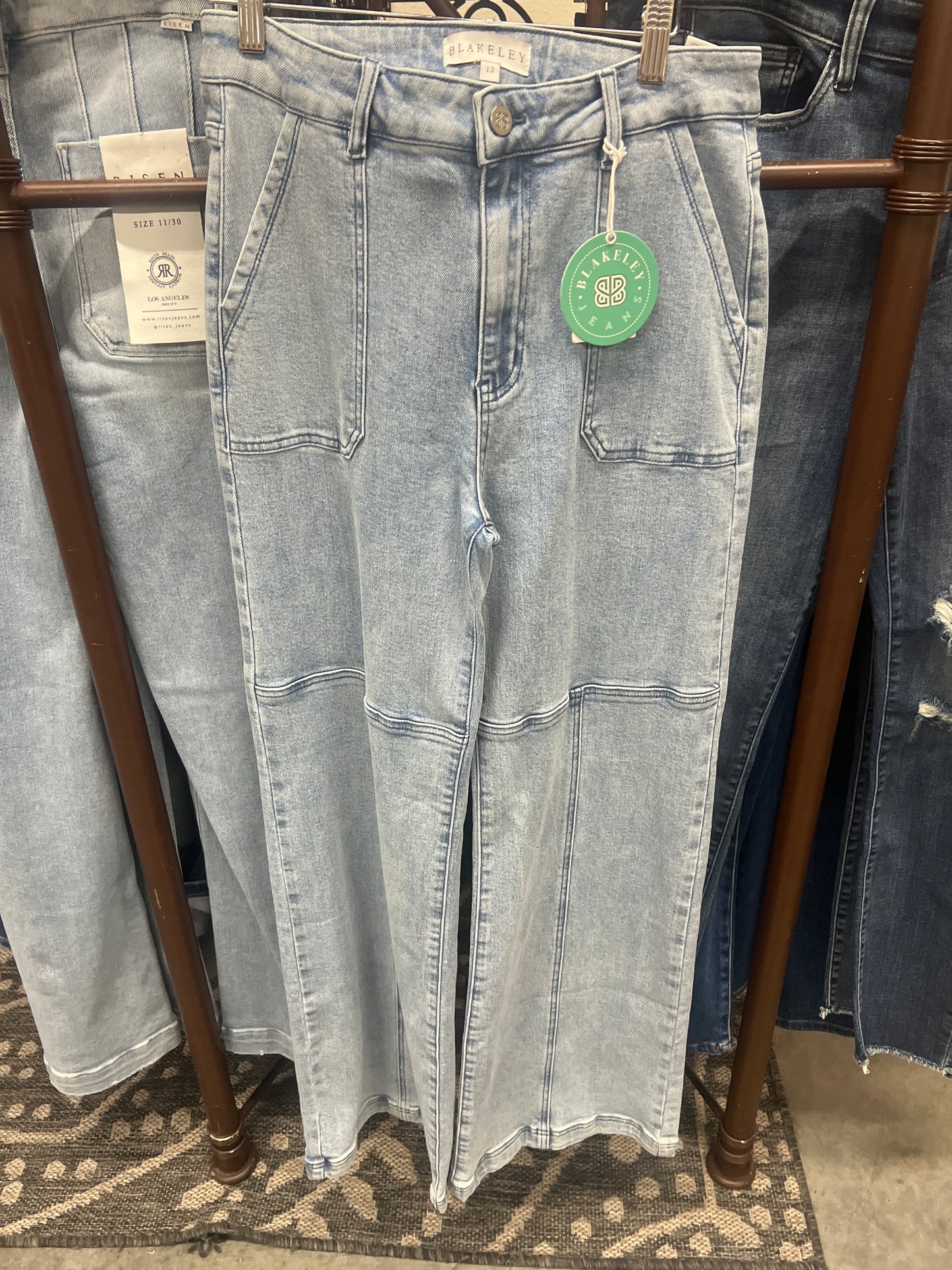 Light blue jeans with a green tag on a wooden hanger.