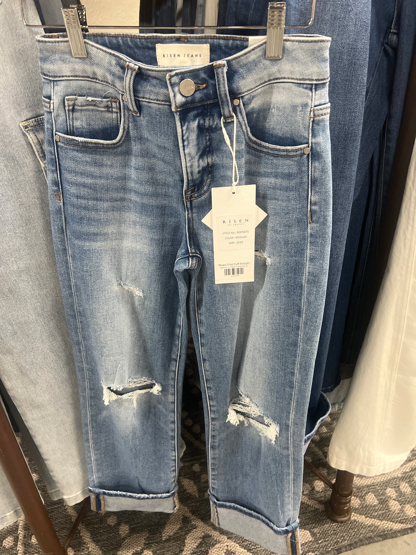Pair of distressed blue jeans with a tag on a rack.