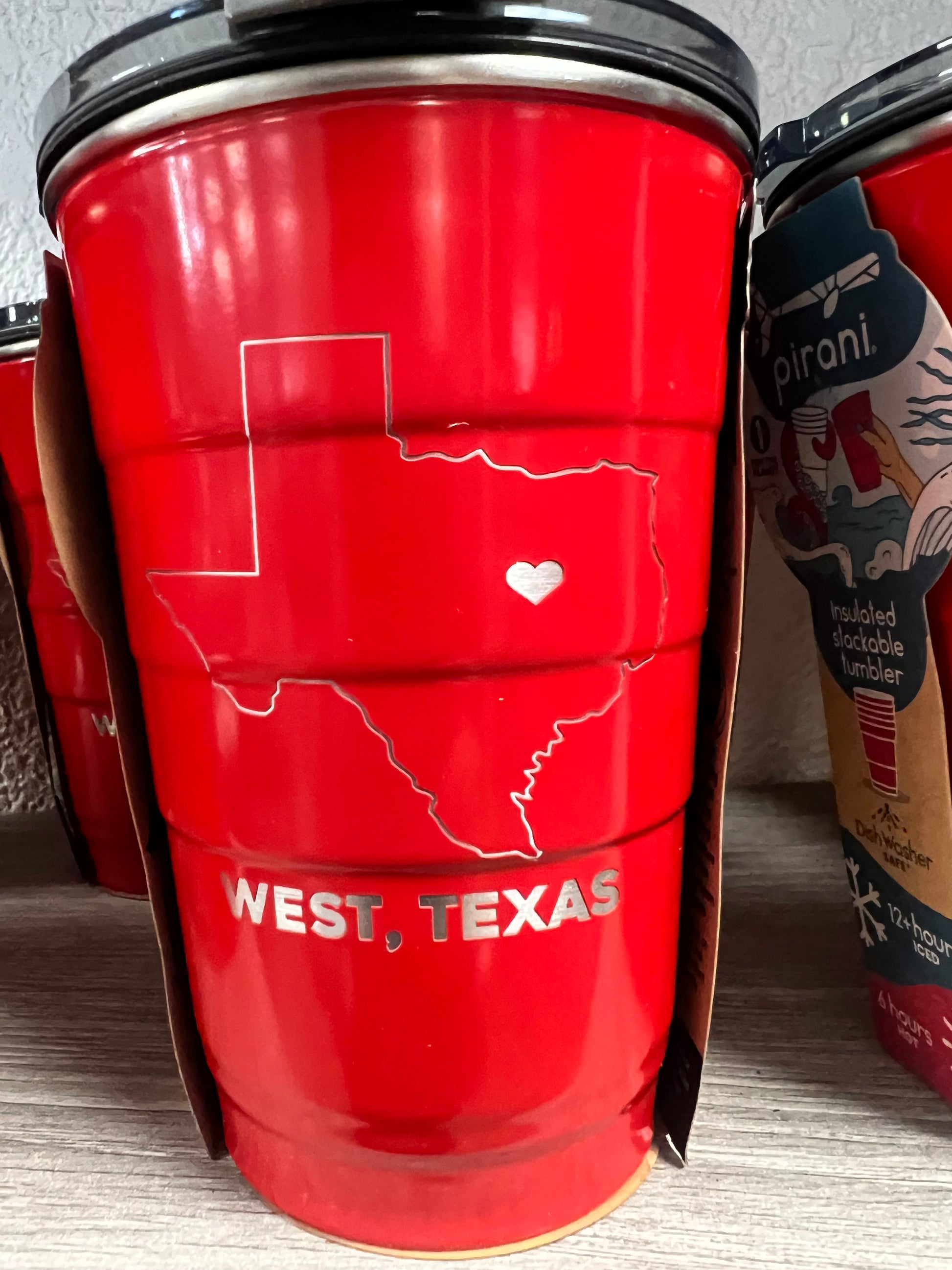 Red thermos with 'West Texas' text on a wooden surface