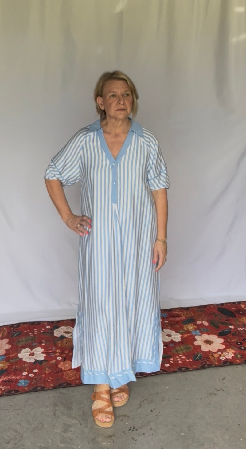 Woman wearing a blue and white striped dress against a plain background