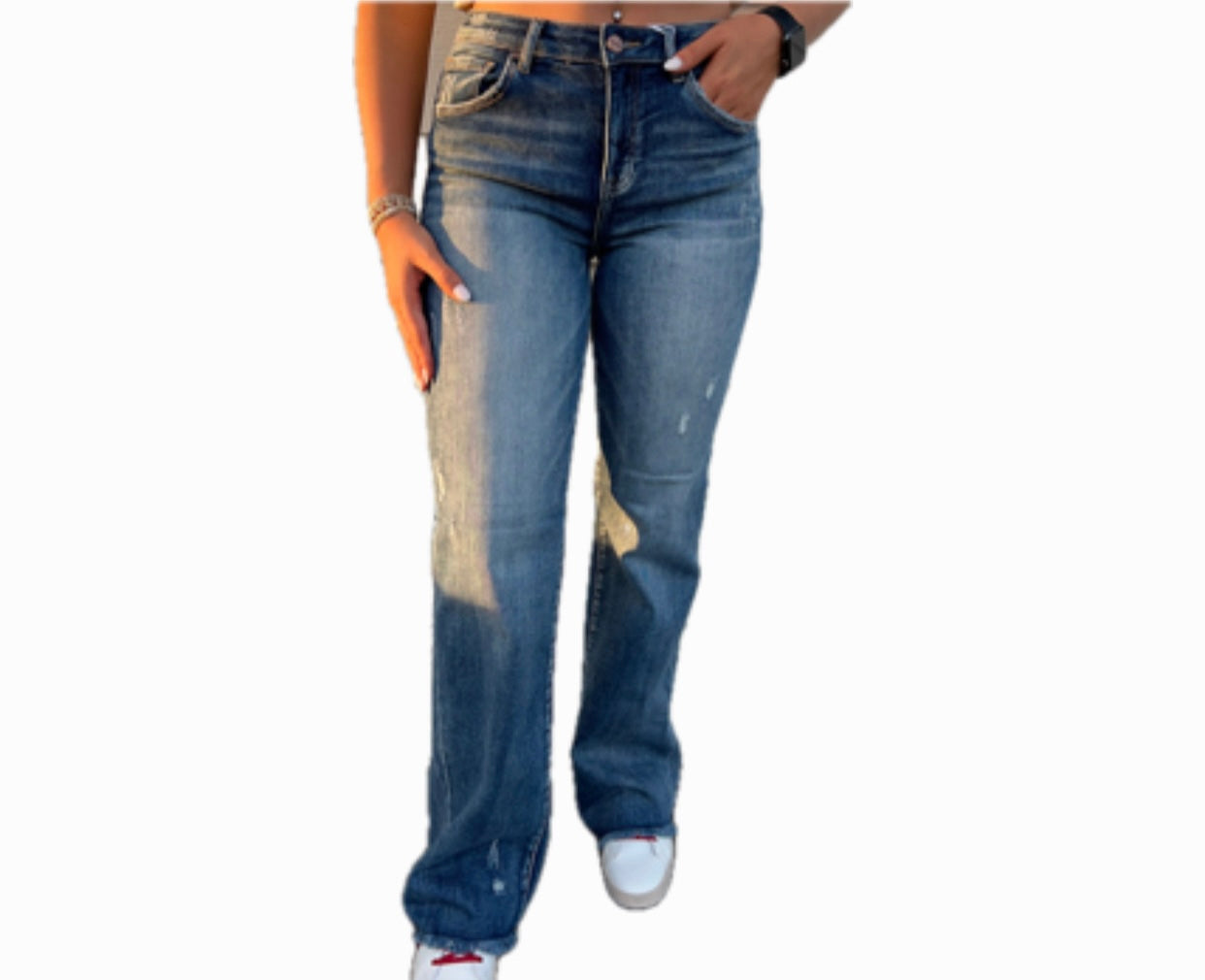 A person wearing high-rise long straight jeans with a dark wash and some distressed details, paired with white sneakers.